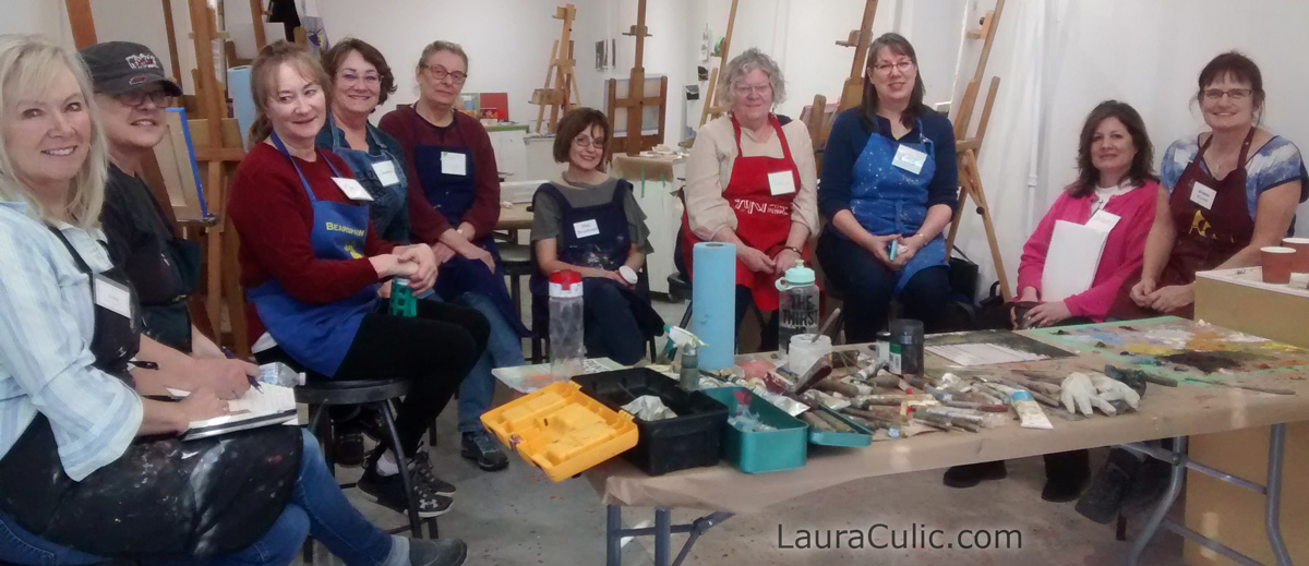 Art students seated around demonstration table, taught by Laura Culic